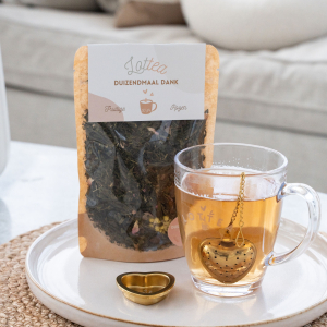 Stazak Lottea thee in de duizendmaal dank smaak met daarnaast een Lottea theemok en een theezakje in een hartvorm.