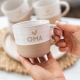 Een theemok die wordt vastgehouden in twee handen. Op de theemok staat oma met daarboven een hartje. De bovenkant van de theemok is wit en de onderkant een aardewerk kleur.